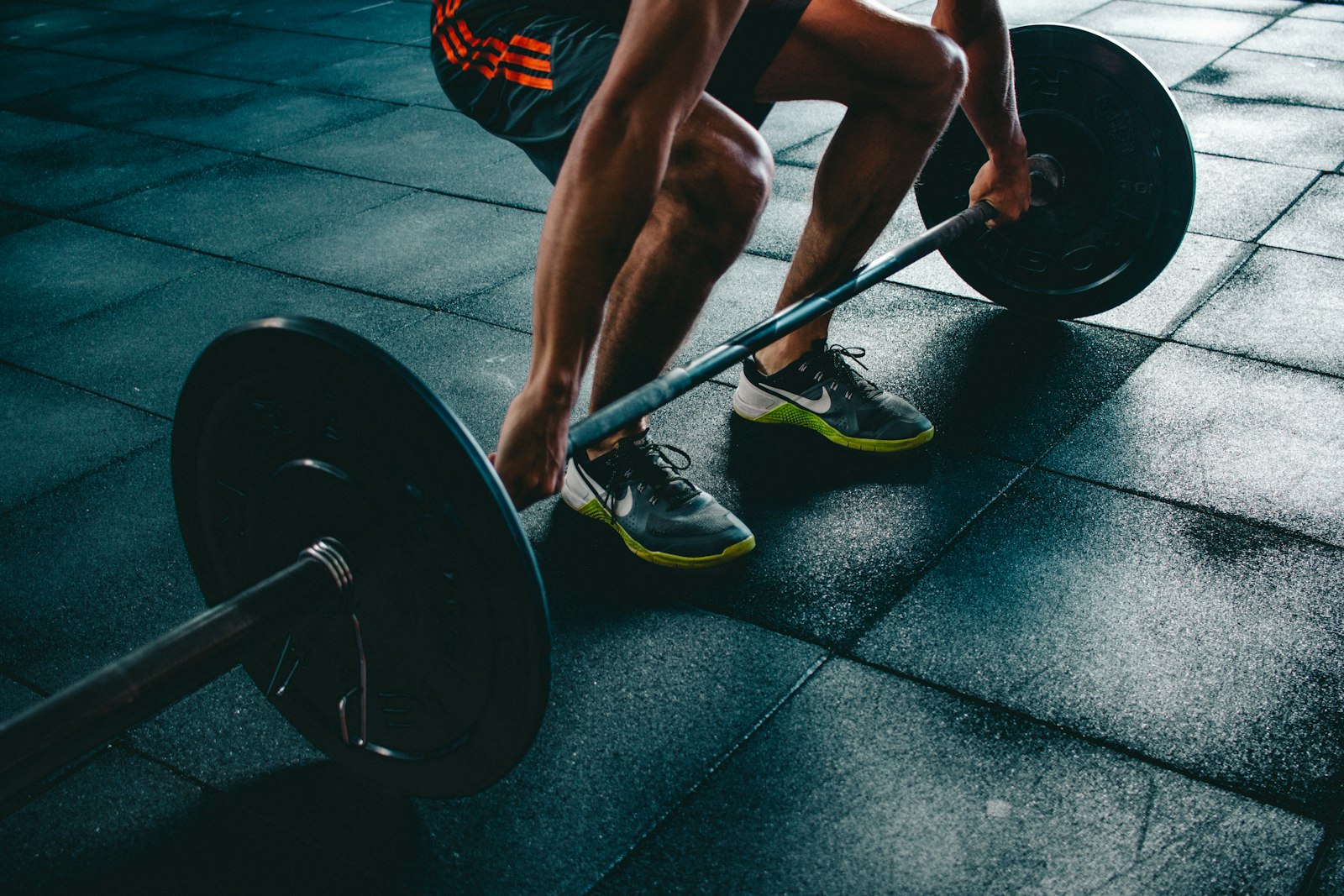 Weightlifter gripping a barbell during a deadlift at a gym